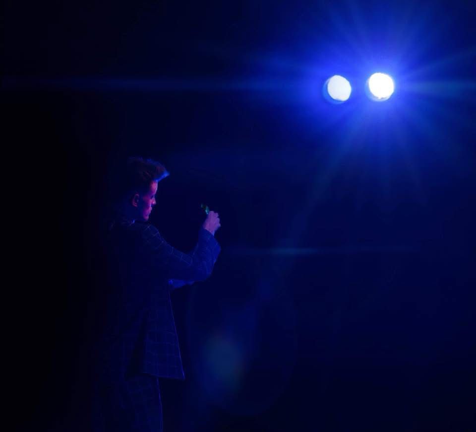George Berryman performing under a spotlight on stage.